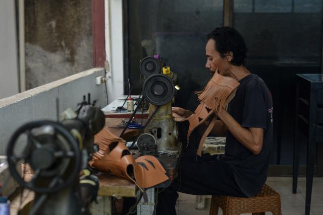 An artisan works on a pair of leather boots at the workshop of Tegep Boots, a popular Indonesian handmade leather boots maker with many dedicated customers in the United States and Europe, in Bandung, West Java on July 15, 2025. At a leather boot shop in the Indonesian city of Bandung, workers handle an order from Texas but owner Etnawati Melani says she fears such business will dwindle when US president Donald Trump's tariffs hit exports. (Photo by Timur MATAHARI / AFP) / TO GO WITH AFP STORY: Indonesia-economy-trade-US, by Yuli Krisna