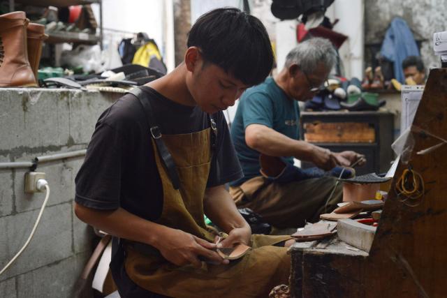 Artisans work on a pair of leather boots for the US market at the workshop of Tegep Boots, a popular Indonesian handmade leather boots maker with many dedicated customers in the United States and Europe, in Bandung, West Java on July 15, 2025. At a leather boot shop in the Indonesian city of Bandung, workers handle an order from Texas but owner Etnawati Melani says she fears such business will dwindle when US president Donald Trump's tariffs hit exports. (Photo by Timur MATAHARI / AFP) / TO GO WITH AFP STORY: Indonesia-economy-trade-US, by Yuli Krisna
