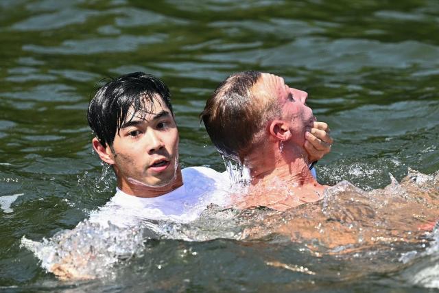 France's swimmer Marc-Antoine Olivier (R) is pulled out from the water in the final of the men's 10km open water swimming event during the 2025 World Aquatics Championships at Sentosa Island in Singapore on July 16, 2025. (Photo by Manan VATSYAYANA / AFP)