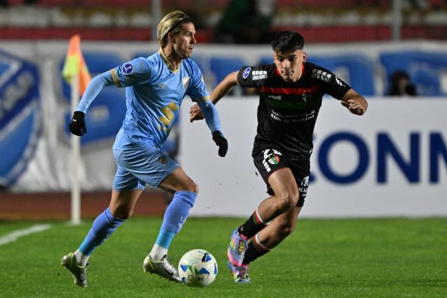 Bolivar's Argentine forward #17 Patricio Rodriguez (L) controls the ball past Palestino's defender #29 Ian Garguez (R) during the Copa Sudamericana knockout round play-off football match between Bolivia's Bolivar and Chile's Palestino at the Hernando Siles stadium in La Paz, on July 16, 2025. (Photo by Aizar RALDES / AFP)