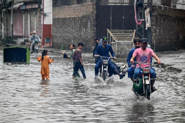 Commuters wade through a flooded street amidst heavy monsoon rains in Rawalpindi on July 17, 2025. Heavy rains have been linked to 54 deaths in the past 24 hours in Pakistan, taking the toll to about 180 since the arrival of the monsoon in late June, the government's disaster agency said on July 17. (Photo by Farooq NAEEM / AFP)