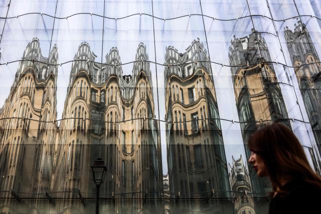 A woman walks past Samaritaine department store decorated with images of Haussmann architecture buildings in Paris on July 18, 2025. (Photo by Behrouz MEHRI / AFP)