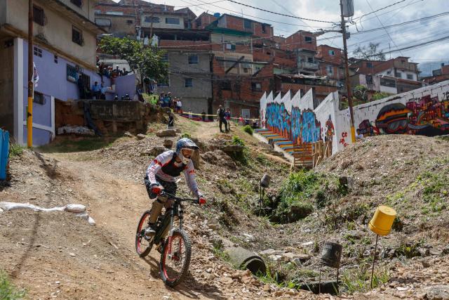 A downhill rider participates in the Petare en Alta urban downhill competition in Petare, Miranda state, Venezuela on July 18, 2025. (Photo by Pedro MATTEY / AFP)