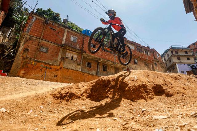 A downhill rider participates in the Petare en Alta urban downhill competition in Petare, Miranda state, Venezuela on July 18, 2025. (Photo by Pedro MATTEY / AFP)