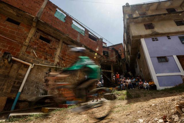 A downhill rider participates in the Petare en Alta urban downhill competition in Petare, Miranda state, Venezuela on July 18, 2025. (Photo by Pedro MATTEY / AFP)