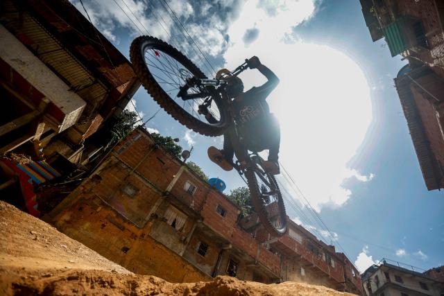 A downhill rider participates in the Petare en Alta urban downhill competition in Petare, Miranda state, Venezuela on July 18, 2025. (Photo by Pedro MATTEY / AFP)