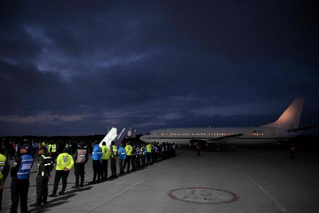 Members of Venezuelan authorities guard the arrival of a plane carrying Venezuelan migrants jailed in El Salvador at Simon Bolivar International Airport in Maiquetia, Venezuela on July 18, 2025. El Salvador freed scores of Venezuelans deported from the United States to a notorious maximum security prison, the outcome of a highly coordinated prisoner swap between Caracas and Washington on July 18, 2025. (Photo by Federico PARRA / AFP)