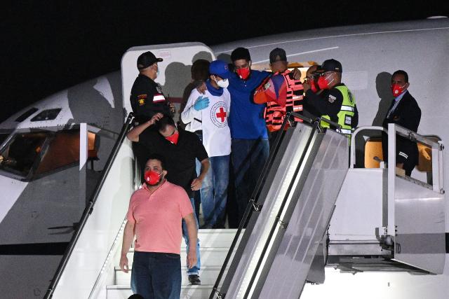 Venezuelan migrants who were jailed in El Salvador get off a plane at Simon Bolivar International Airport in Maiquetia, Venezuela on July 18, 2025. El Salvador freed scores of Venezuelans deported from the United States to a notorious maximum security prison, the outcome of a highly coordinated prisoner swap between Caracas and Washington on July 18, 2025. (Photo by Federico PARRA / AFP)