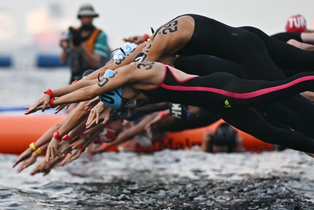 Swimmers dive into the water to start the final of the women's 3km sprint open water swimming event during the 2025 World Aquatics Championships at Sentosa Island in Singapore on July 19, 2025. (Photo by Manan VATSYAYANA / AFP)