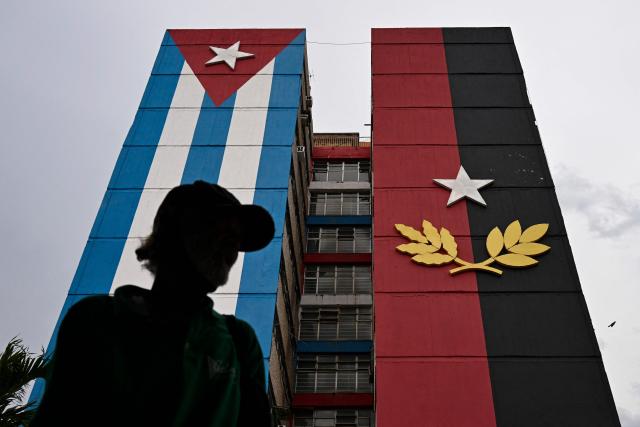 A man walks past a 26th of July Movement flag painted on a building in tribute to the 72nd anniversary of the assault on the Moncada Barracks in 1953, in Ciego de Avila province, Cuba on July 23, 2025. The Cuban government on July 26 will commemorate the 72nd anniversary of the guerrilla assault on the Moncada Barracks, widely regarded as the beginning of the Cuban Revolution. (Photo by YAMIL LAGE / AFP)