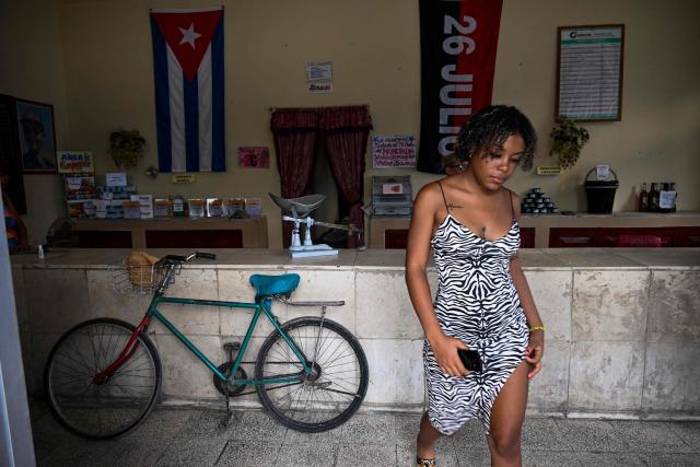 A woman leaves a store decorated with a 26th of July Movement flag during the commemoration of the 72nd anniversary of the assault on the Moncada Barracks in 1953, in Ciego de Avila province, Cuba on July 23, 2025. The Cuban government on July 26 will commemorate the 72nd anniversary of the guerrilla assault on the Moncada Barracks, widely regarded as the beginning of the Cuban Revolution. (Photo by YAMIL LAGE / AFP)