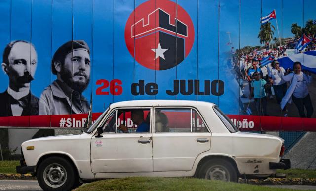 A car drives past a sign honoring the 72nd anniversary of the assault on the Moncada Barracks in 1953, in Ciego de Avila province, Cuba on July 23, 2025. The Cuban government on July 26 will commemorate the 72nd anniversary of the guerrilla assault on the Moncada Barracks, widely regarded as the beginning of the Cuban Revolution. (Photo by YAMIL LAGE / AFP)