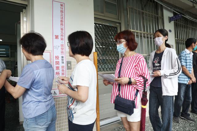 Voters wait in line to cast their ballots at a polling station during the recall election in Taipei on July 26, 2025. Taiwanese voters turned out at schools, churches and community centres on July 26 to cast their ballot in a high-stakes recall election that could give President Lai Ching-te's party control of the parliament. (Photo by I-Hwa Cheng / AFP)