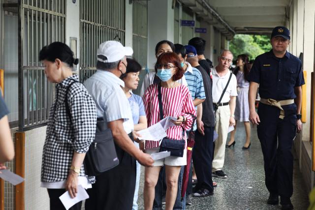 Voters wait in line to cast their ballots at a polling station during the recall election in Taipei on July 26, 2025. Taiwanese voters turned out at schools, churches and community centres on July 26 to cast their ballot in a high-stakes recall election that could give President Lai Ching-te's party control of the parliament. (Photo by I-Hwa Cheng / AFP)