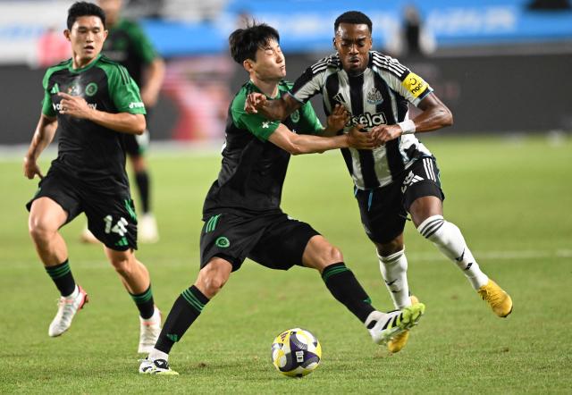 Newcastle United's Joe Willock (R) fights for the ball with Team K-League's Kim Dong-hyeon (C) during the friendly football match between English Premier League football club Newcastle United and South Korean K League stars, Team K-League, in Suwon on July 30, 2025. (Photo by Jung Yeon-je / AFP)