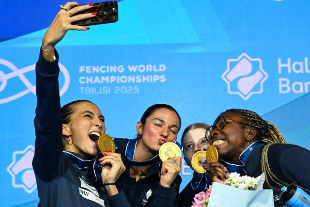 Gold medallists team France, including Sara Balzer, Toscane Tori and Sarah Noutcha, celebrate during the medal ceremony for the women's sabre team competition at the FIE Fencing World Championships in Tbilisi on July 30, 2025. (Photo by Vano SHLAMOV / AFP)