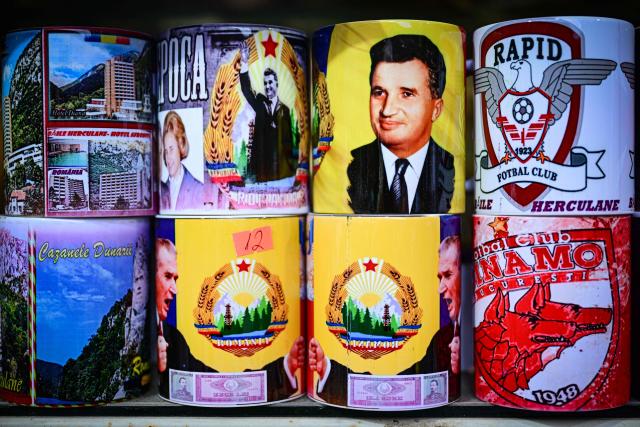 A souvenir shop displays mugs with the portraits of late communist dictator Nicolae Ceausescu, his wife Elena and communist-erac banknotes in Baile Herculane, south-western Romania on July 29, 2025. A recent survey shows a worring nostalgic trend such as 55.8% of Romanians believe that the communist regime was rather a good thing for Romania, 48.4% think that life was better before 1989 compared to today, 77.2% believe that Romania was a richer country before 1989, 75.1% believe movies produced in Romania before 1989 were better than today.  President Nicusor Dan's reacts with a tweet about the survey: "I am deeply concerned about the results of the study presented today". "In my opinion, the main reason why more and more Romanians are idealizing communism is the deep disappointment with the political class of the last three decades." (Photo by Daniel MIHAILESCU / AFP)