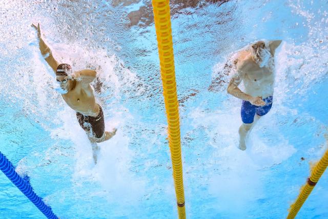 An underwater view shows Tunisia's swimmer Ahmed Jaouadi (L) and Germany's swimmer Sven Schwarz as they compete in  a heat of the men's 1500m freestyle swimming event during the 2025 World Aquatics Championships in Singapore on August 2, 2025. (Photo by Manan VATSYAYANA / AFP)