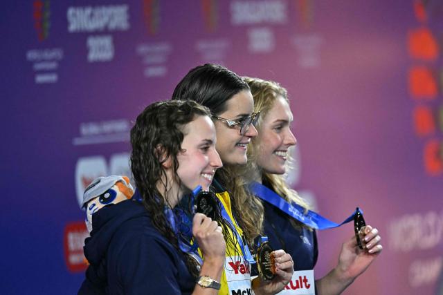 (L-R) Silver medallist US' swimmer Regan Smith, gold medallist Australia's swimmer Kaylee McKeown and bronze medallist US' swimmer Claire Curzan celebrate on the podium the women's 200m backstroke swimming event during the 2025 World Aquatics Championships in Singapore on August 2, 2025. (Photo by MANAN VATSYAYANA / AFP)