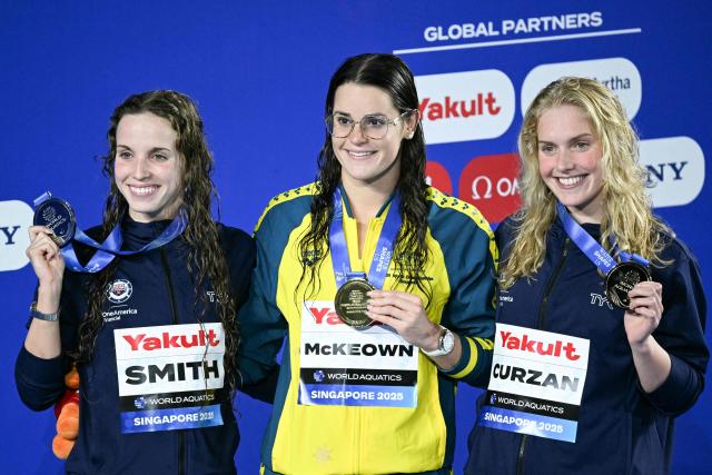 (L-R) Silver medallist US' swimmer Regan Smith, gold medallist Australia's swimmer Kaylee McKeown and bronze medallist US' swimmer Claire Curzan celebrate on the podium the women's 200m backstroke swimming event during the 2025 World Aquatics Championships in Singapore on August 2, 2025. (Photo by Oli SCARFF / AFP)