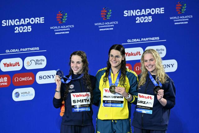 (L-R) Silver medallist US' swimmer Regan Smith, gold medallist Australia's swimmer Kaylee McKeown and bronze medallist US' swimmer Claire Curzan celebrate on the podium the women's 200m backstroke swimming event during the 2025 World Aquatics Championships in Singapore on August 2, 2025. (Photo by Oli SCARFF / AFP)
