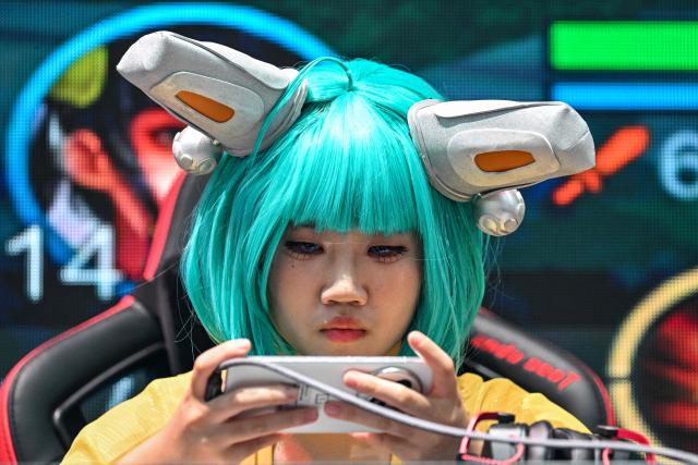 A gamer is seen playing a video game during the China Digital Entertainment Expo and Conference known as ChinaJoy, at the Shanghai New International Expo Centre in Shanghai on August 4, 2025. (Photo by Hector RETAMAL / AFP)