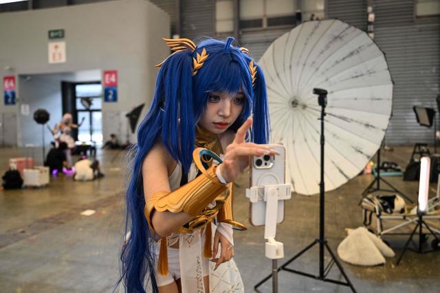A cosplayer looks at her smartphone during the China Digital Entertainment Expo and Conference known as ChinaJoy, at the Shanghai New International Expo Centre in Shanghai on August 4, 2025. (Photo by Hector RETAMAL / AFP)
