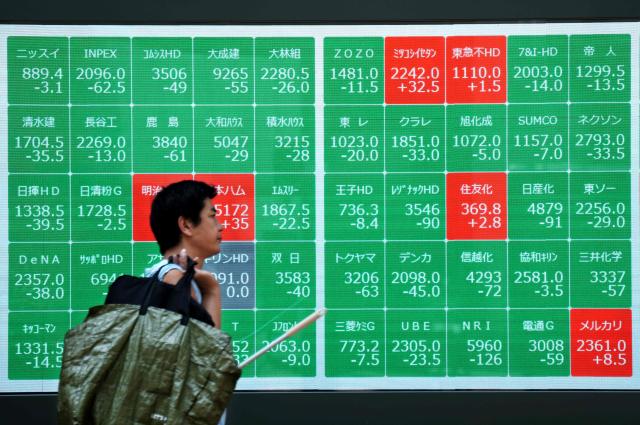 A man walks past an electronic quotation board displaying the Nikkei 225 stock prices on the Tokyo Stock Exchange in Tokyo on August 4, 2025. (Photo by Kazuhiro NOGI / AFP)