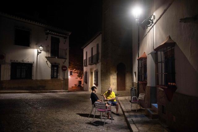 People gather outdoors to sit in front of their houses in order to cool off during a heatwave in Ronda, southern Spain on August 4, 2025. As the second heatwave of the year begins on the Iberian Peninsula,  temperatures are forecast to be between 5C to 10C above seasonal norms, with Spain's Aemet weather agency warning it was "likely that the heatwave lasts long and persists till at least next Sunday". (Photo by JORGE GUERRERO / AFP)