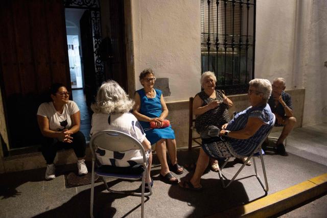 People gather outdoors to sit in front of their houses in order to cool off during a heatwave in Ronda on August 4, 2025. As the second heatwave of the year begins on the Iberian Peninsula,  temperatures are forecast to be between 5C to 10C above seasonal norms, with Spain's Aemet weather agency warning it was "likely that the heatwave lasts long and persists till at least next Sunday". (Photo by JORGE GUERRERO / AFP)
