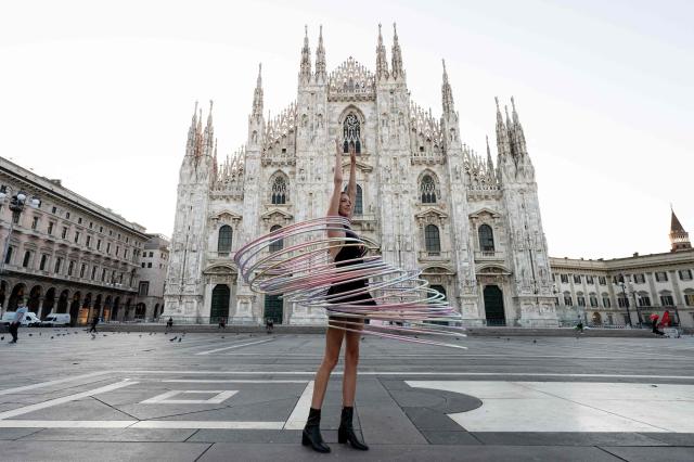 Acrobatic artist Kate Ryan hula-hoops with multiple hoops early in the morning in Doumo's Square, central Milan, on August 5, 2025. (Photo by Stefano RELLANDINI / AFP)