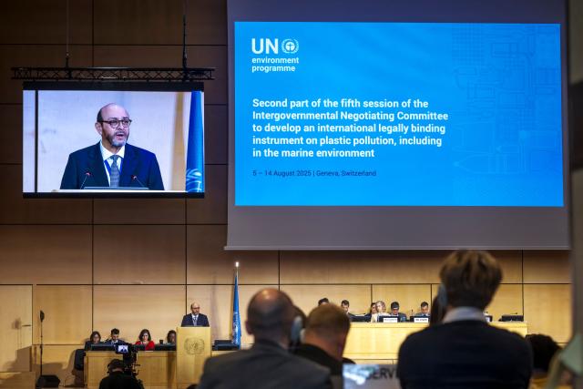 The chairman of the negotiations, Ecuadorian ambassador Luis Vayas Valdivieso (5th-L) is displayed on a screen (Top-L) as he delivers a speech during the plastics treaty negotiations at the United Nations Offices in Geneva on August 5, 2025. Countries were to start the clock on August 5, 2025, on 10 days of talks aimed at hammering out a landmark global treaty on combating the scourge of plastic pollution. Three years of negotiations hit the wall in South Korea in December 2024 when a group of oil-producing states blocked a consensus. (Photo by Fabrice COFFRINI / AFP)