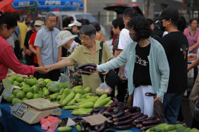 Customers shop for vegetables at a traditional market in Shenyang, China's northern Liaoning province on August 9, 2025. (Photo by AFP) / China OUT