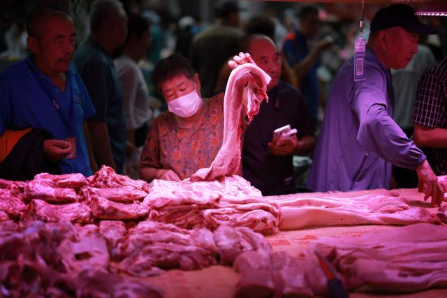 Customers shop for meat at a traditional market in Shenyang, China's northern Liaoning province on August 9, 2025. (Photo by AFP) / China OUT