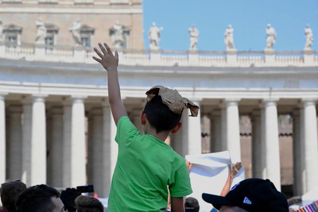 A child with a leaf on his head attends the Angelus prayer at St. Peter's Square in The Vatican on August 10, 2025. (Photo by Andreas SOLARO / AFP)
