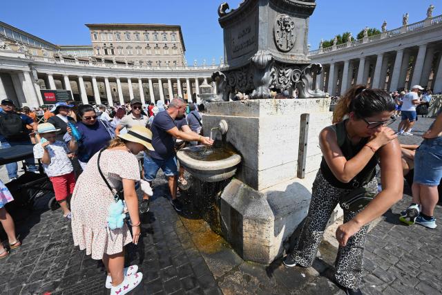 People refresh themselves with water from a fountain as they attend the Angelus prayer at St. Peter's Square in The Vatican on August 10, 2025. (Photo by Andreas SOLARO / AFP)