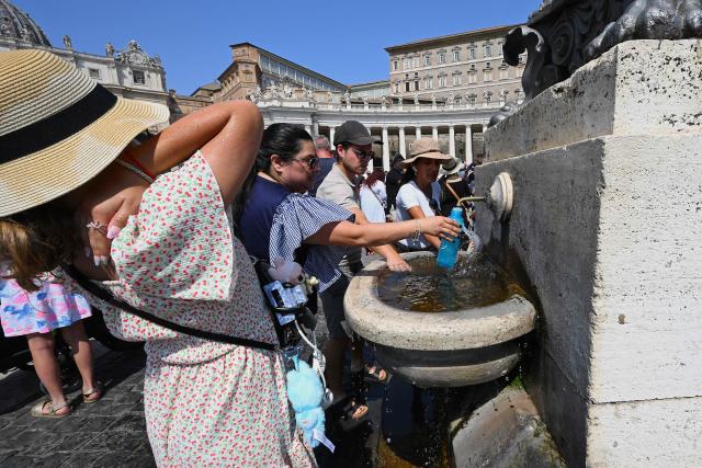 People refresh themselves with water from a fountain as they attend the Angelus prayer at St. Peter's Square in The Vatican on August 10, 2025. (Photo by Andreas SOLARO / AFP)