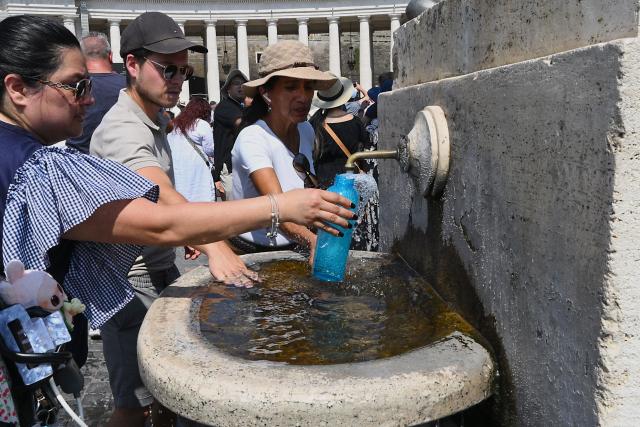 People fill bottles and refresh themselves with water from a fountain as they attend the Angelus prayer at St. Peter's Square in The Vatican on August 10, 2025. (Photo by Andreas SOLARO / AFP)