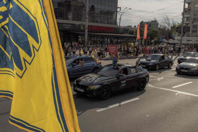 Campaigners hold placards and wave flags as they take part in a rally to raise awareness to the fate of Ukrainian prisoners of war from the Azov Brigade and other military units, in Kyiv, on August 10, 2025, amid the Russian invasion of Ukraine. (Photo by Roman PILIPEY / AFP)