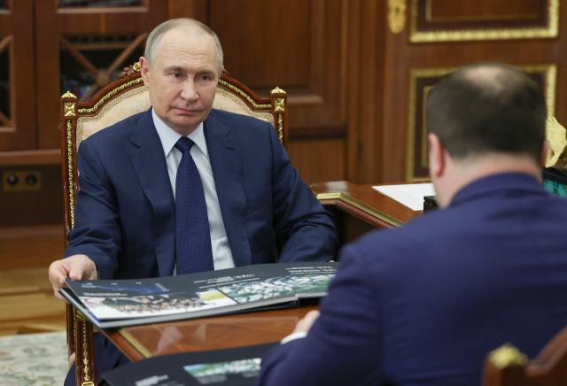 In this pool photograph distributed by the Russian state agency Sputnik, Russia's President Vladimir Putin (L) meets with Omsk Region Governor Vitaly Khotsenko in Moscow on August 11, 2025. (Photo by Vyacheslav PROKOFYEV / POOL / AFP)