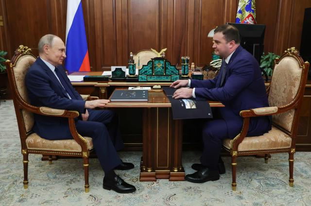In this pool photograph distributed by the Russian state agency Sputnik, Russia's President Vladimir Putin (L) meets with Omsk Region Governor Vitaly Khotsenko in Moscow on August 11, 2025. (Photo by Vyacheslav PROKOFYEV / POOL / AFP)