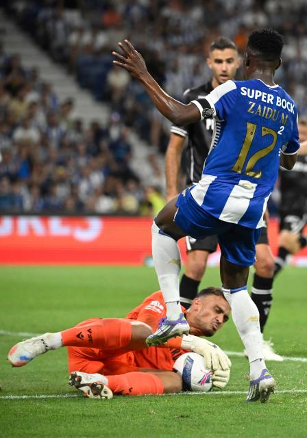 Vitoria Guimaraes' Brazilian goalkeeper #27 Charles saves the ball next to FC Porto's Nigerian defender #12 Zaidu Sanusi during the Portuguese League football match between FC Porto and Vitoria Guimaraes SC at Dragao stadium in Porto on August 11, 2025. (Photo by MIGUEL RIOPA / AFP)