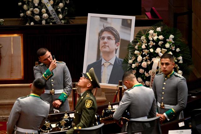 Police officers stand in front of a tribute to late Colombian presidential candidate Miguel Uribe at Congress in Bogota on August 11, 2025. Colombian presidential candidate Miguel Uribe died two months after being shot in the head at a campaign event, his wife announced early August 11, 2025. The legislator's condition had returned to critical after he suffered a new brain hemorrhage related to the assassination attempt during a rally on June 7, in which he was shot three times, twice in the head. (Photo by Raul ARBOLEDA / AFP)