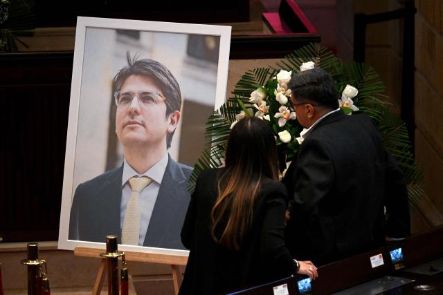 People stand in front of a tribute to late Colombian presidential candidate Miguel Uribe at Congress in Bogota on August 11, 2025. Colombian presidential candidate Miguel Uribe died two months after being shot in the head at a campaign event, his wife announced early August 11, 2025. The legislator's condition had returned to critical after he suffered a new brain hemorrhage related to the assassination attempt during a rally on June 7, in which he was shot three times, twice in the head. (Photo by Raul ARBOLEDA / AFP)