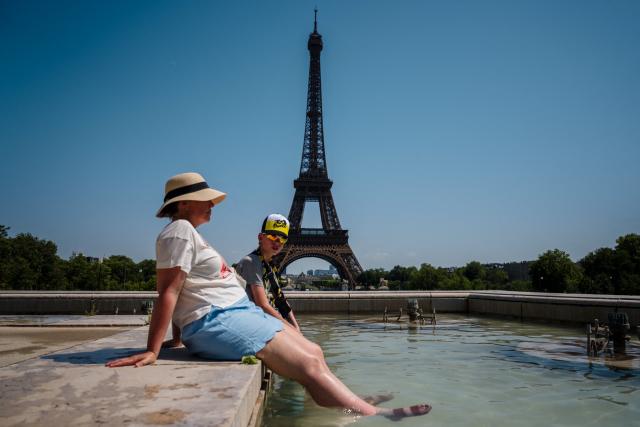 (FILES) Tourists cool off in the Trocadero Fountain, in front of the Eiffel Tower in Paris, on July 1, 2025, as temperatures in France are expected to hit a peak today, according to the Meteo France weather agency, with some areas expected to soar beyond 40 degrees Celsius (104 degrees Fahrenheit). The red heat alert remains in force until August 13 in the 14 departments of the South-West and the Centre-East concerned, Meteo-France announced in its latest bulletin, on August 12, 2025. (Photo by Dimitar DILKOFF / AFP)
