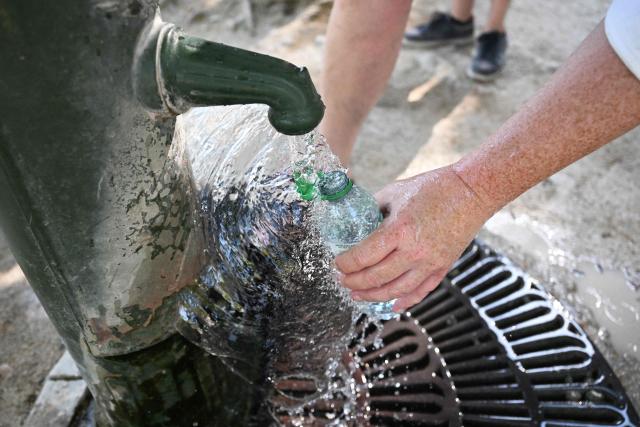 (FILES) A pedestrian fills a bottle with water pouring from a public fountain at the Tuileries Garden in Paris on August 11, 2025, amid a heatwave in Europe. The red heat alert remains in force until August 13 in the 14 departments of the South-West and the Centre-East concerned, Meteo-France announced in its latest bulletin, on August 12, 2025. (Photo by Martin LELIEVRE / AFP)