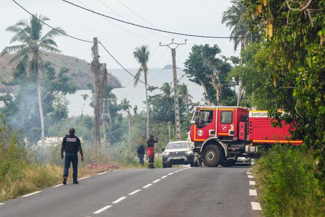 A firetruck maneuvers on a road lined with burning vegetation during a wildfire in the village of Ironi Be, in the township of Dembeni, on the French Indian Ocean territory of Mayotte on August 12, 2025. Since Cyclone Chido hit Mayotte on December 14, 2024, fires have been fueled by fallen vegetation. (Photo by Marine GACHET / AFP)