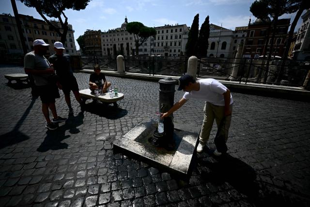 A man fills up a bottle of water from a Nasone typical roman drinking fountain, in downtown Rome on August 13, 2025. Italy is facing extreme heat until mid-August as temperatures above 40 degrees centigrade is gripping the entire country at least until the August 15th bank holiday weekend. (Photo by Filippo MONTEFORTE / AFP)