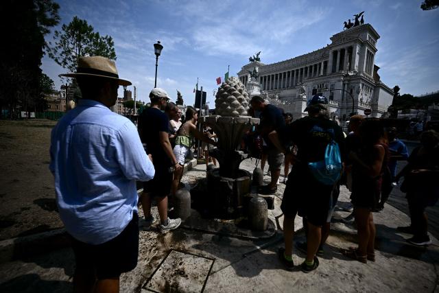 People queue to fill up empty bottles with water from the "fontana della Pigna" Rome Piazza Venezia on August 13, 2025. Italy is facing extreme heat until mid-August as temperatures above 40 degrees centigrade is gripping the entire country at least until the August 15th bank holiday weekend. (Photo by Filippo MONTEFORTE / AFP)