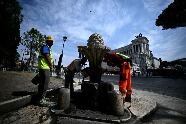 People queue to fill up empty bottles with water from the "fontana della Pigna" Rome Piazza Venezia on August 13, 2025. Italy is facing extreme heat until mid-August as temperatures above 40 degrees centigrade is gripping the entire country at least until the August 15th bank holiday weekend. (Photo by Filippo MONTEFORTE / AFP)